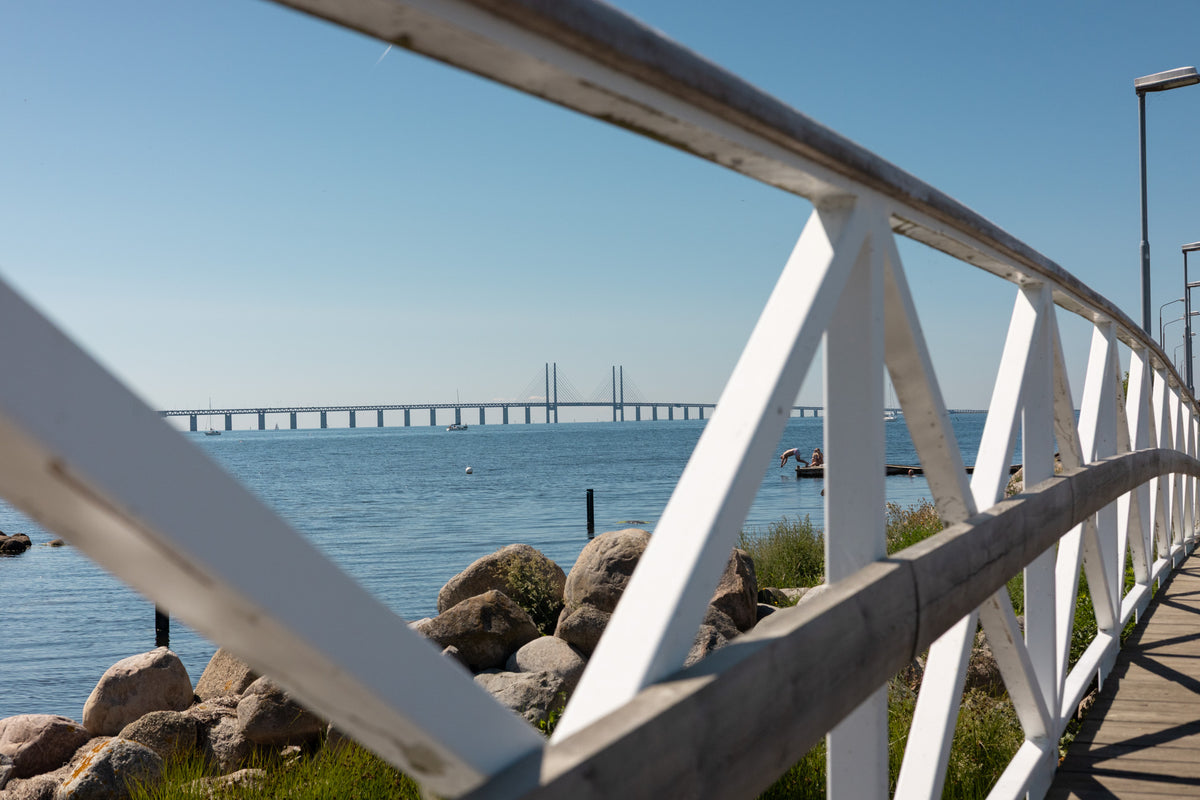 Photo of a small pedestrian bridge and a pier in Malmö with the Oresund bridge in the background.