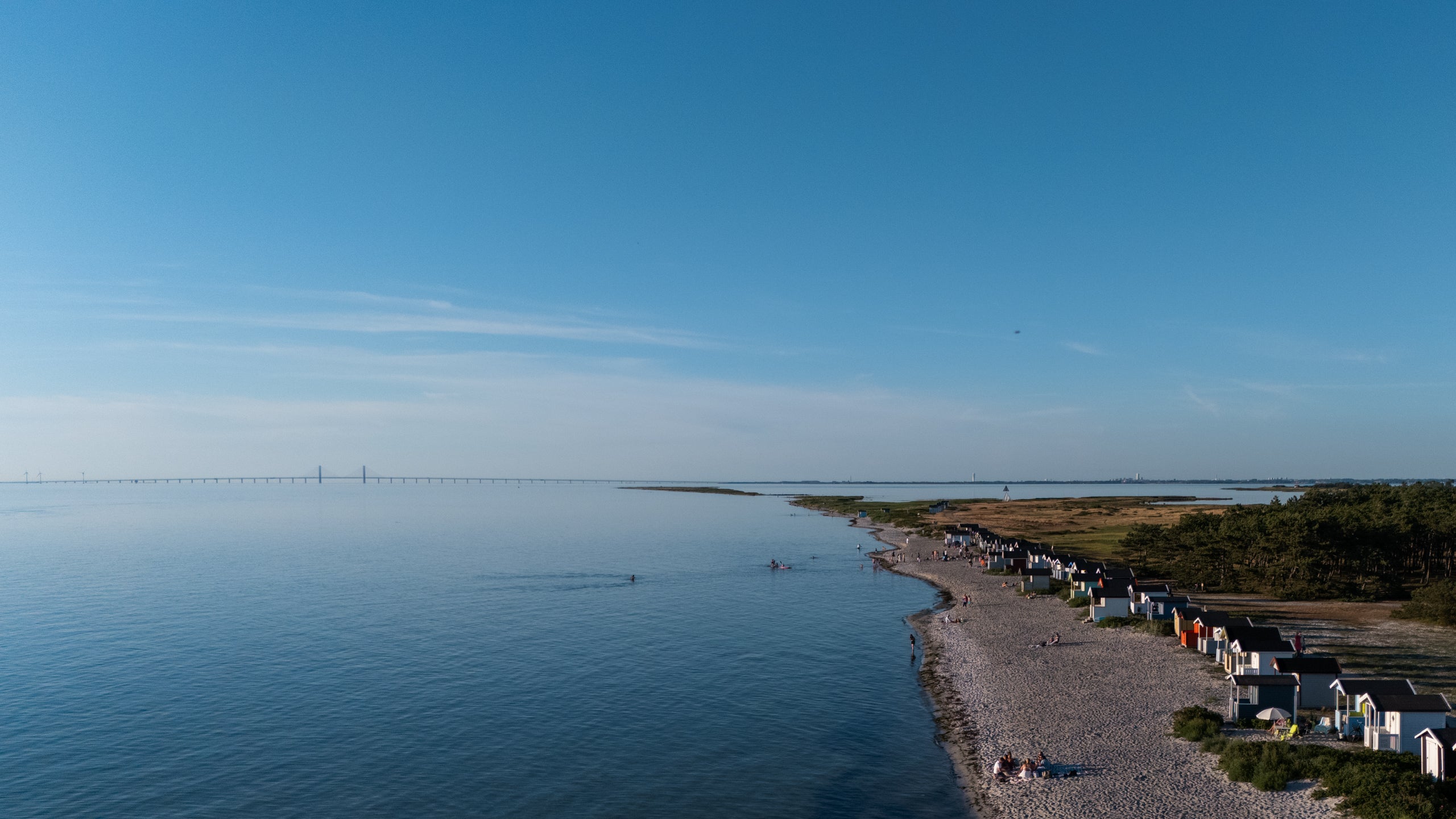 Drone photo in Falsterbo Sweden showing the coastline with summer storage colorful houses and the Oresund Bridge in the background.