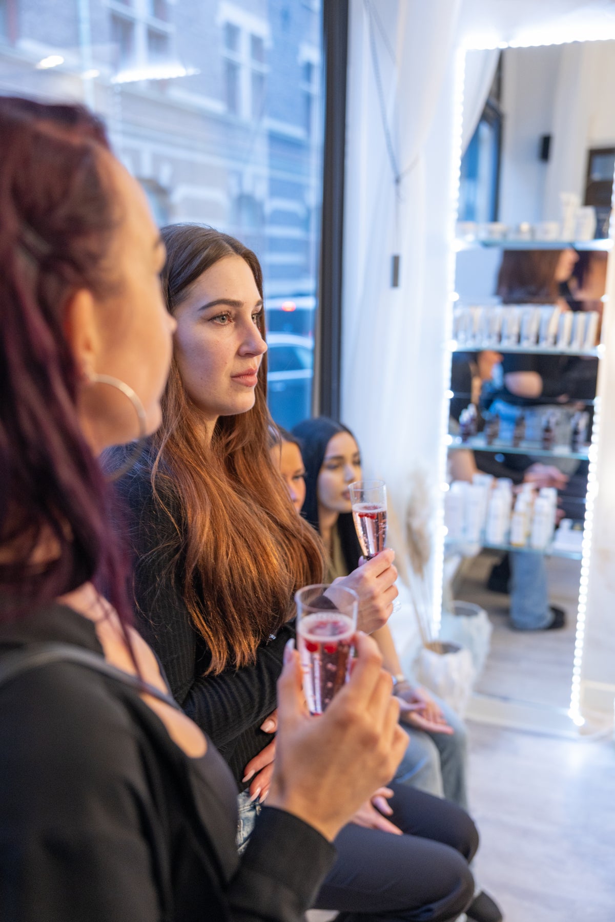 Event photo taken by Photographer Thiago Mazzeo. In the photo, 4 women watching an event holding a drink on their hand.